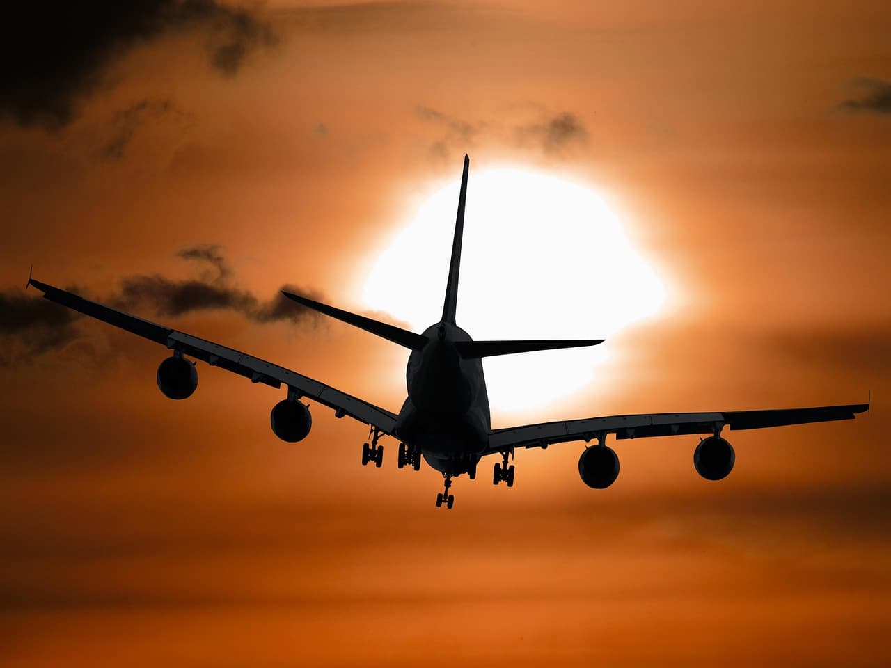 Silhouette d'un avion de ligne à l'atterrissage devant un soleil couchant