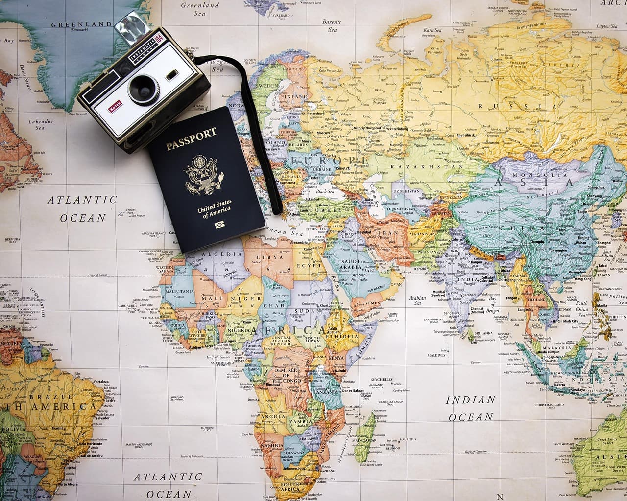 Passeport et appareil photo posés sur une carte du monde