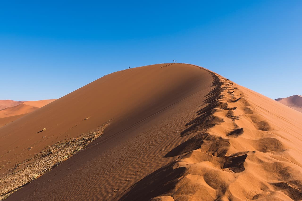 Randonneurs minuscules sur la crête d'une dune du désert du Namib